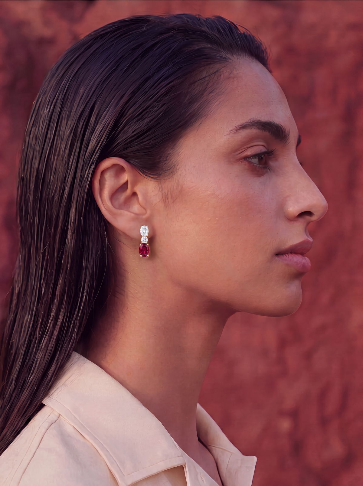 woman with diamond and ruby earrings on a brick red stone wall background