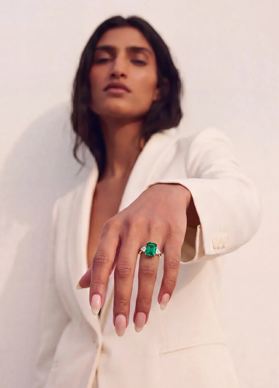 woman in white suite wearing an emerald and diamond ring 