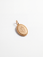 A small oval gold pendant with a decorative border and an engraved symbol in the center, shown on a clean white background.