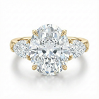 Gold ring with a large diamond and smaller diamonds on the sides against a white background