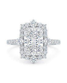 Diamond ring in white gold with a central radiant cut diamond with a diamond halo against a white background