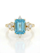 Gold ring with a blue gemstone and diamond accents on a white background