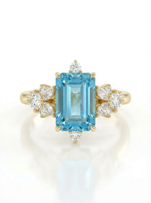 Gold ring with a blue gemstone and diamond accents on a white background