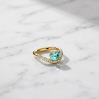 Gold ring with a green gemstone on a marble surface