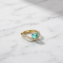 Gold ring with a green gemstone on a marble surface