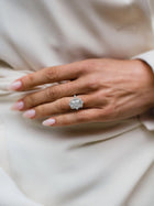 Close-up of a hand wearing a diamond ring on a light fabric background