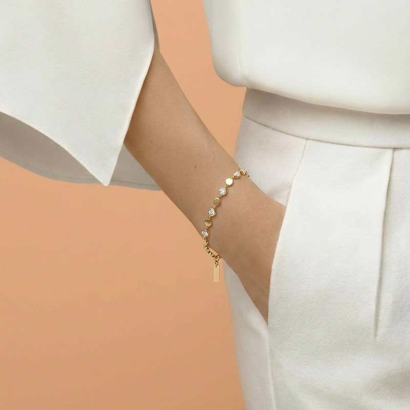 Gold bracelet with pearls on a wrist against a white background