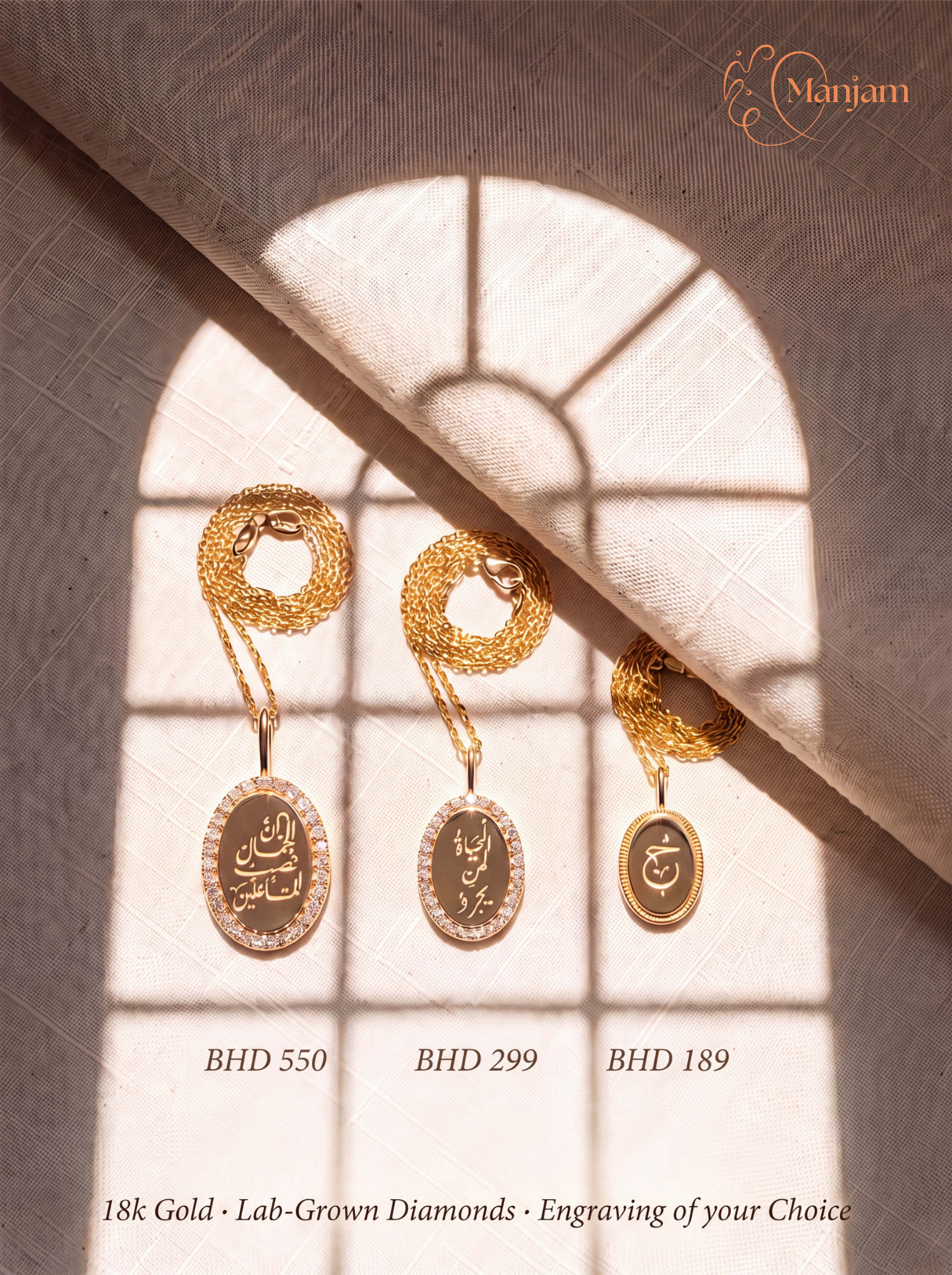 Three gold pendant necklaces with Arabic calligraphy engravings displayed on a beige fabric background under a window shadow pattern. The brand name 'Manjam' is visible in the top right corner, and the prices are shown below each necklace.