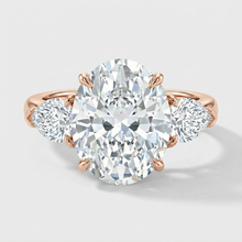Rose gold ring with a large diamond and smaller diamonds on the sides against a light gray background
