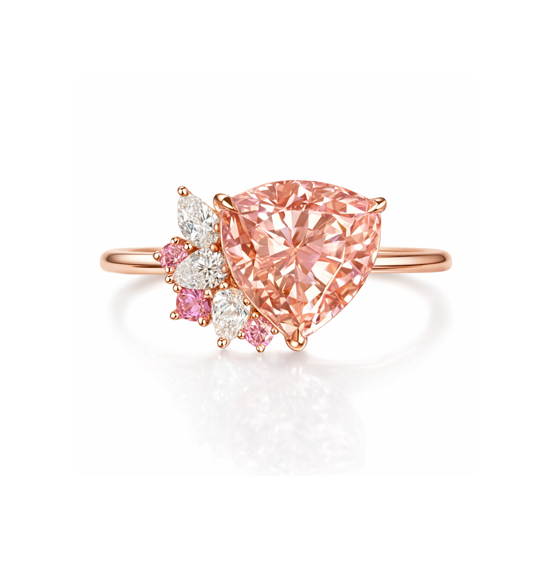 Rose gold ring with an orangy pink  trillion-shaped diamond and smaller pink and white diamonds on a white background