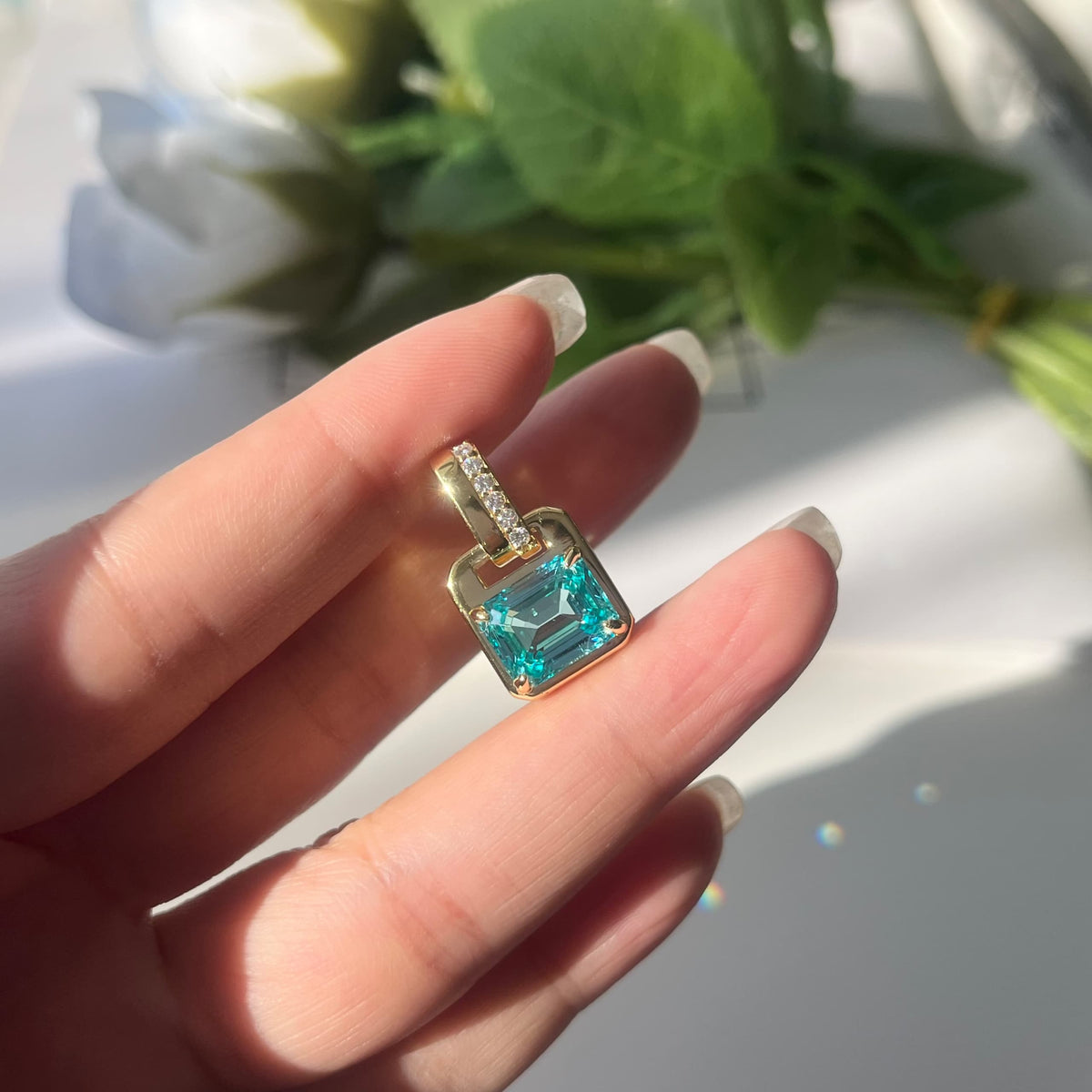 Gold ring with a blue gemstone held by a hand against a blurred natural background