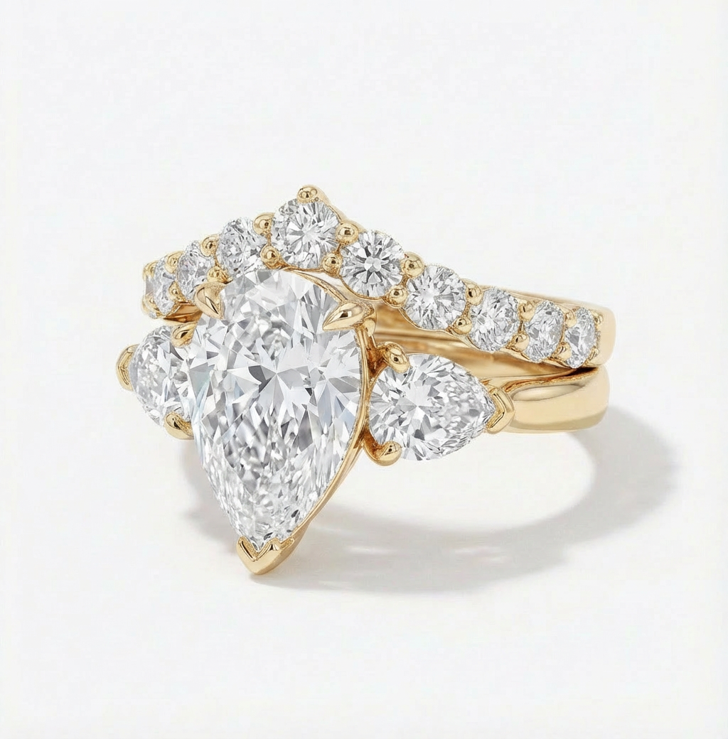 Gold ring with a pear-shaped diamond and smaller round diamonds on a light gray background