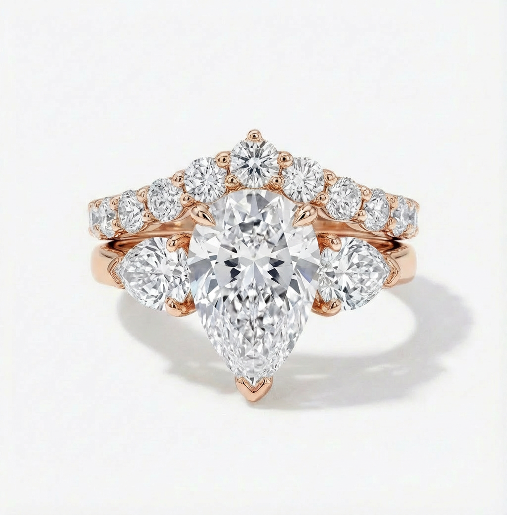 Rose gold diamond ring with pear-shaped center stone on a white background
