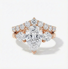 Rose gold diamond ring with pear-shaped center stone on a white background