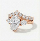 Rose gold ring with a pear-shaped diamond and smaller round diamonds on a light background