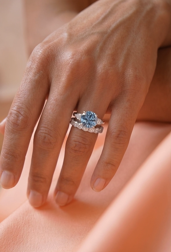 woman wearing a blue diamond ring with a full eternity diamond wedding band walking in an upscale space 
