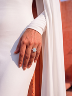 close up on a hand of a model wearing a diamond ring with a central radiant cut diamond with a diamond halo 