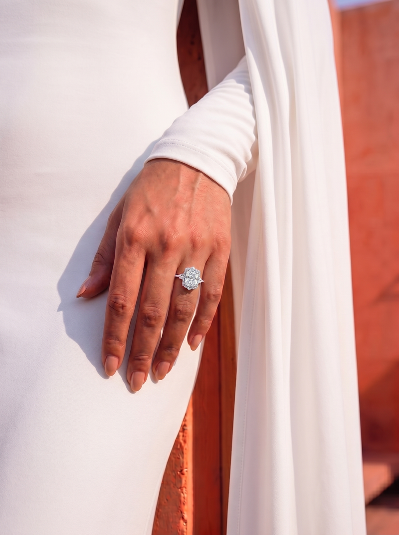 close up on a hand of a model wearing a diamond ring with a central radiant cut diamond with a diamond halo 