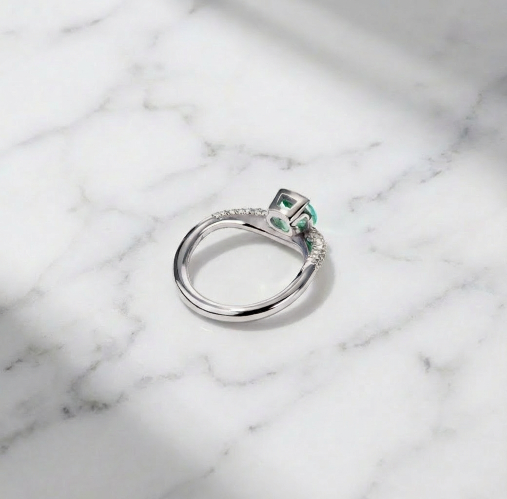 Silver ring with a green gemstone on a marble surface