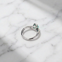 Silver ring with a green gemstone on a marble surface