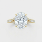 Gold ring with a large diamond and smaller diamonds on the band against a light gray background