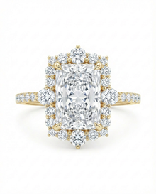 Diamond ring with a large central radiant cut diamond with a diamond halo in yellow gold on a white background