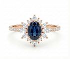 Rose gold ring with a blue gemstone and diamond accents on a white background