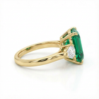 Gold ring with a green gemstone and diamond on a white background