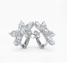 Pair of floral white diamond earrings on a white background