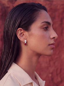 woman with diamond and ruby earrings on a brick red stone wall background