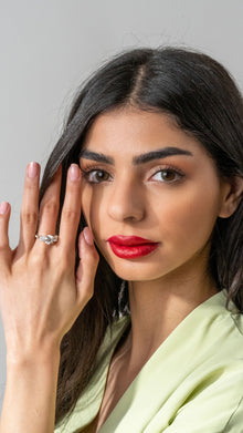 Woman with red lipstick and a ring on her finger against a gray background